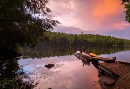 Dock leading up to a lake during sunset with orange and purple skies